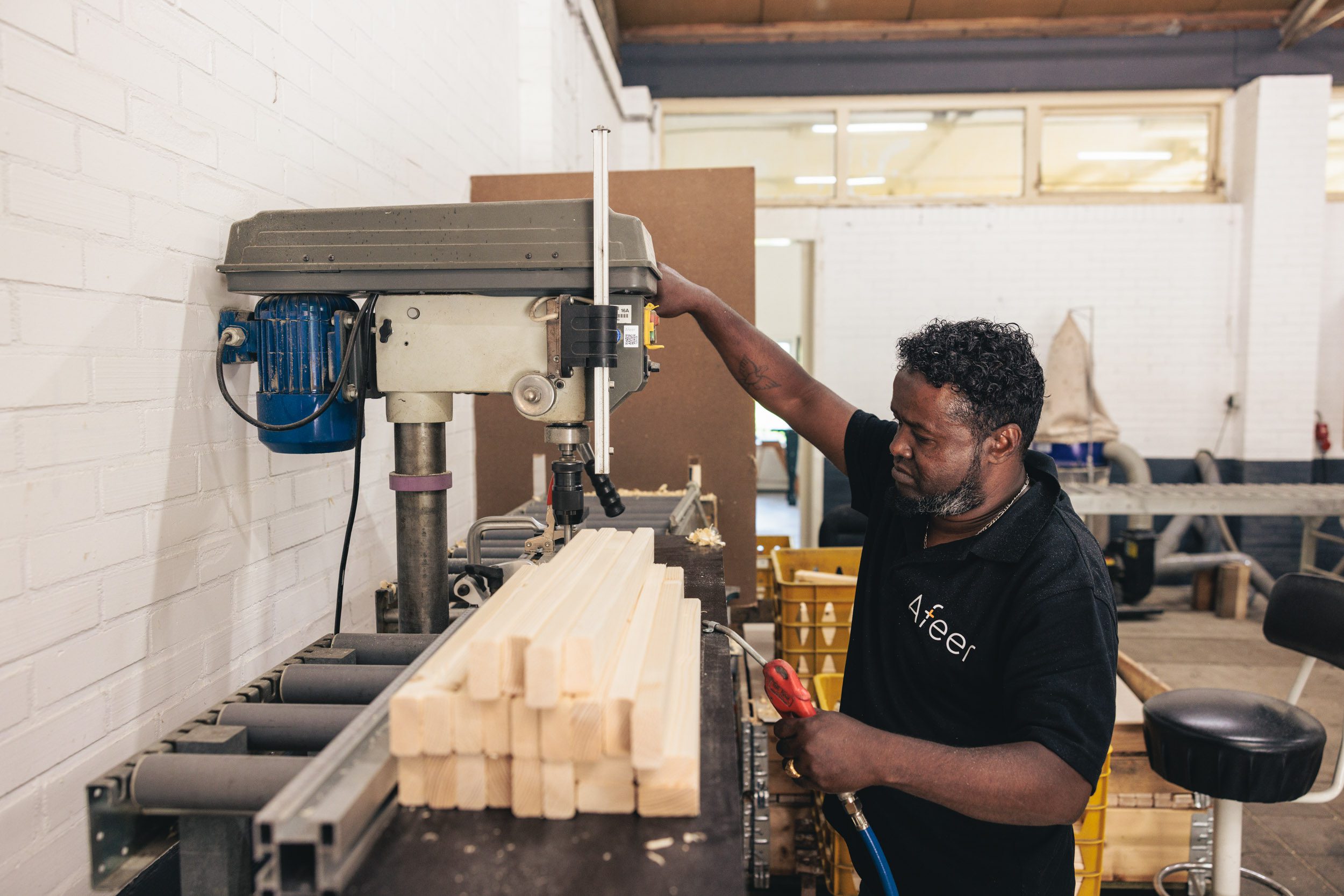 Een medewerker van Afeer is met een machine hout aan het zagen