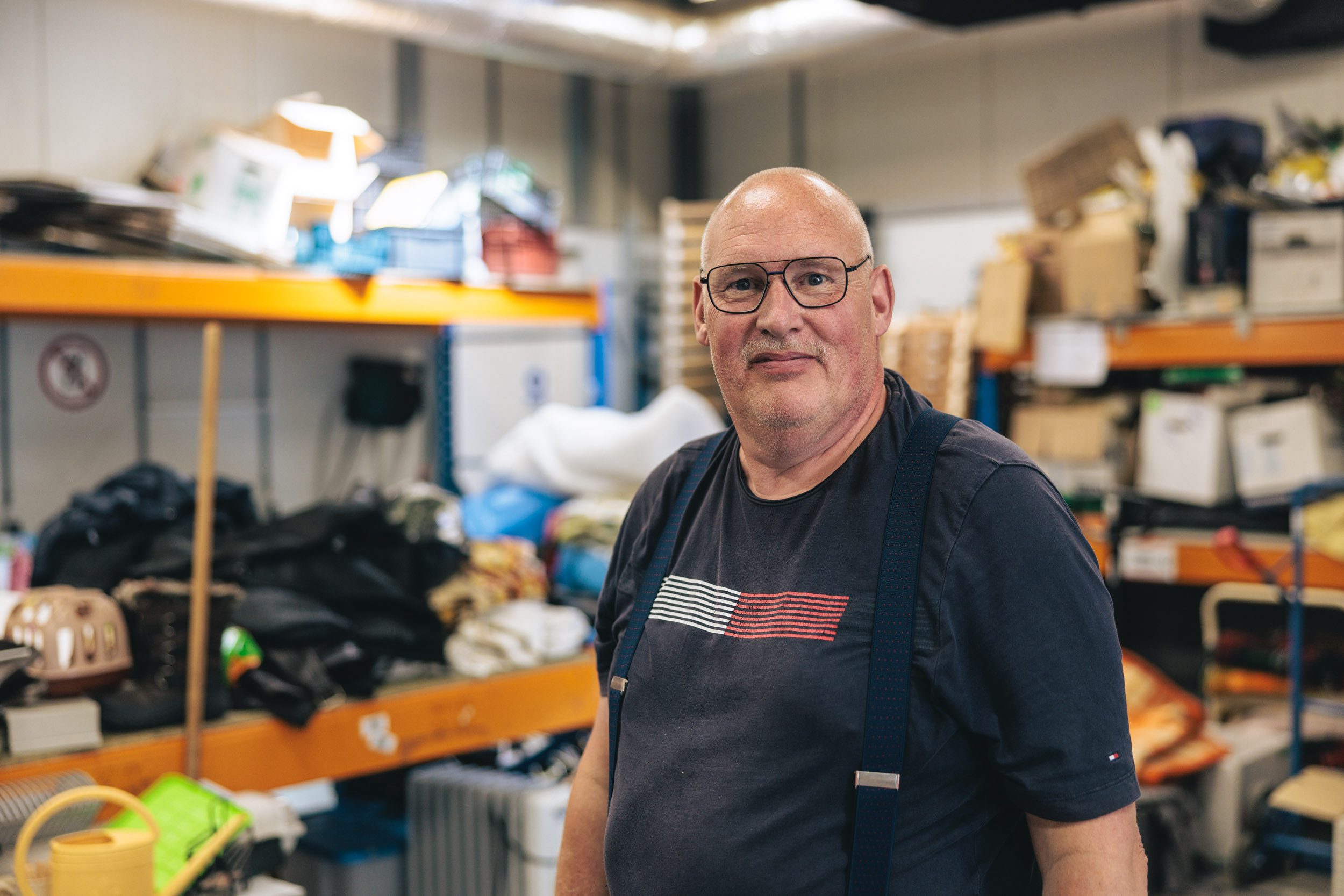 medewerker van de kringloopwinkel van Afeer in Oude Pekela met op de achtergrond schappen met te sorteren spullen