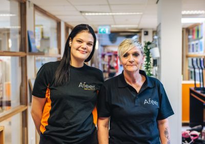 Twee schoonmaaksters van Afeer staan naast elkaar en lachen naar de camera