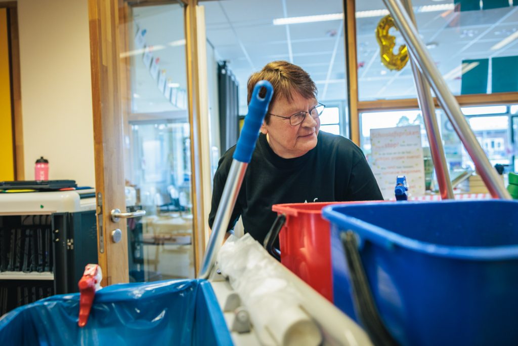 Een schoonmaakmedewerkster van Afeer achter haar schoonmaakkar